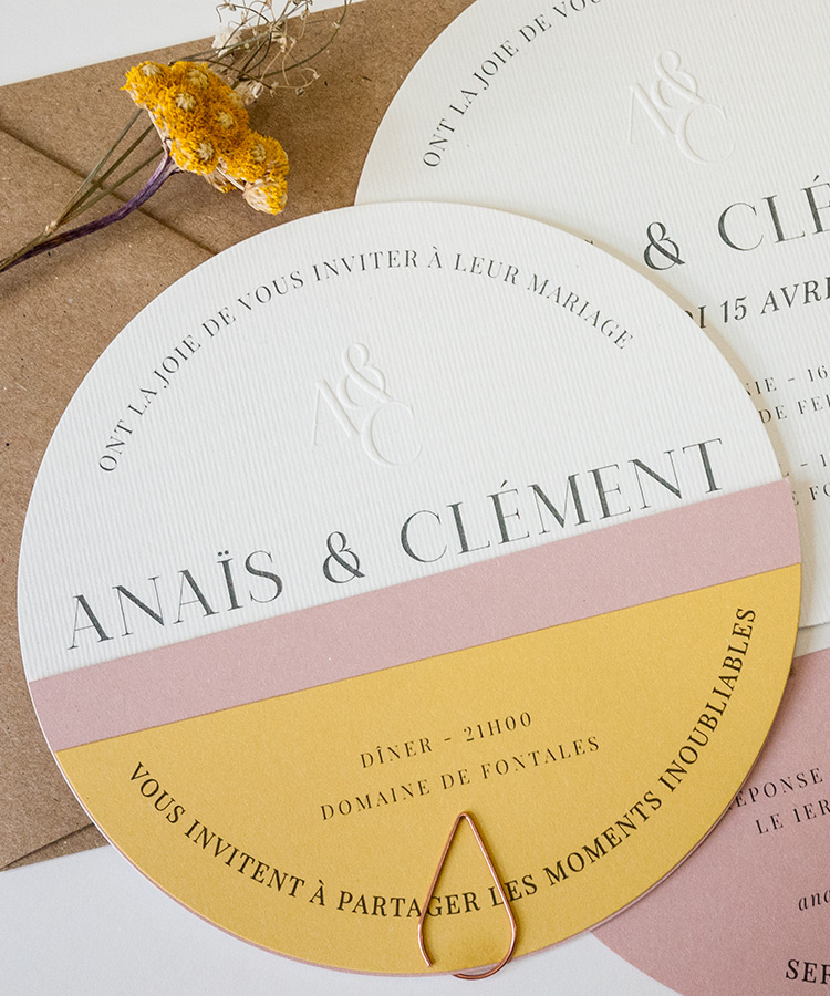 Une invitation de mariage de forme ronde sur papiers de couleur pastel