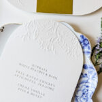 Menu mariage blanc sur papier texturé avec gaufrage floral et impression argent