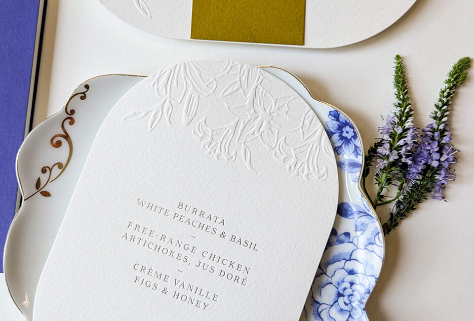 Menu mariage blanc sur papier texturé avec gaufrage floral et impression argent
