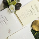 Faire-part de mariage blanc avec fleurs gaufrées et typographie en dorure cuivre