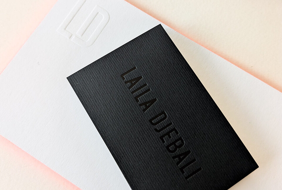 Carte de visite pour consultante avec marquage à chaud noir brillant sur papier noir mat texturé, accompagnée d’une carte de correspondance blanche avec logo débossé.